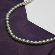 服の上に置いて撮影した真珠のネックレスの商品写真