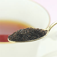 金のスプーンに入れた紅茶の茶葉を撮影した写真