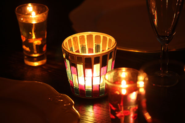 天井照明の小さなオレンジ色の電球で撮影したキャンドル卓のイメージ写真